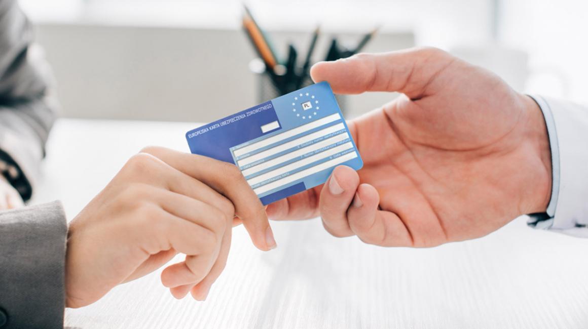 Zbliżenie na ręce. Pacjent podaje lekarzowi swoją kartę EKUZ.