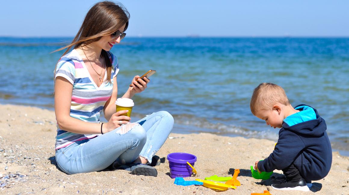 Matka z komórka, chłopiec, plaża