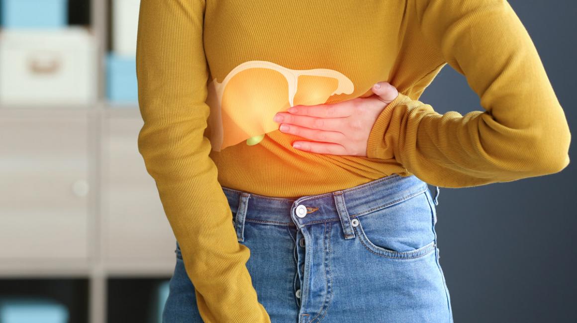 Tułów osoby, która trzyma się za bok. Na tym tle dorysowana wątroba