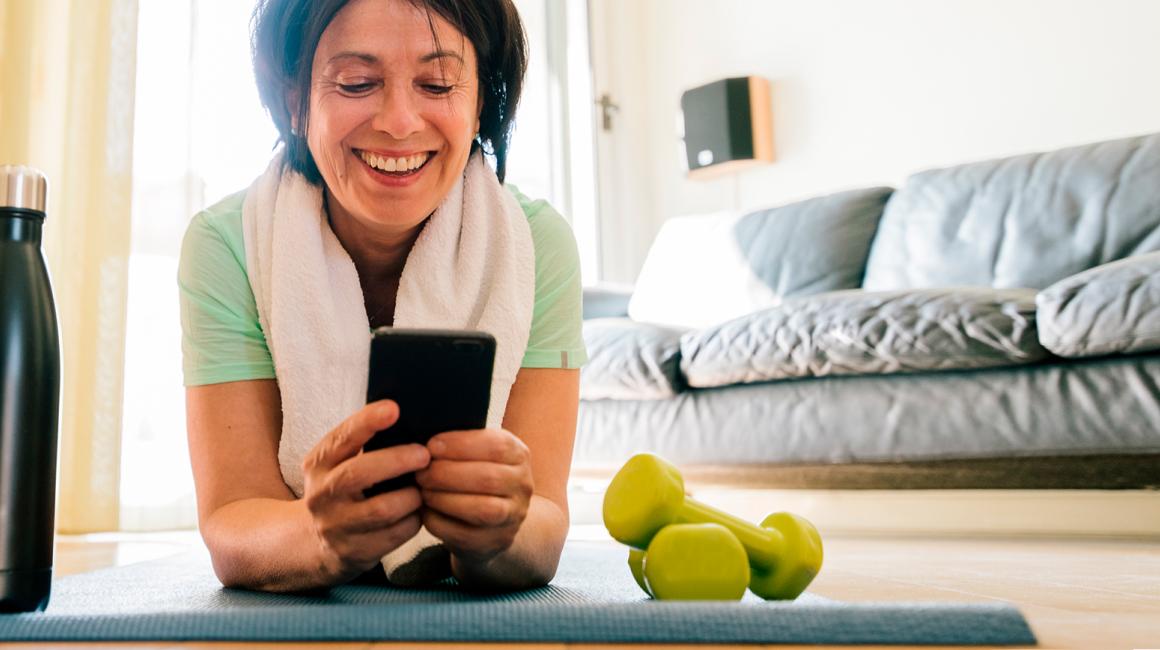 kobieta na macie patrzy na komórkę