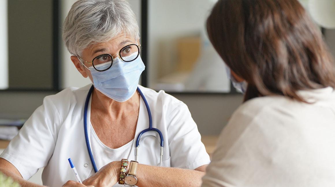 Pacjentka widoczna od tyłu rozmawiająca ze starszą lekarką. Siedzą. Widoczne tyłko górne partie sylwetek.