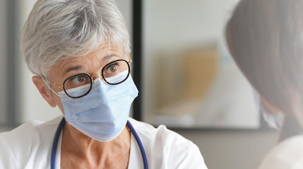 Pacjentka widoczna od tyłu rozmawiająca ze starszą lekarką. Siedzą. Widoczne tyłko górne partie sylwetek.