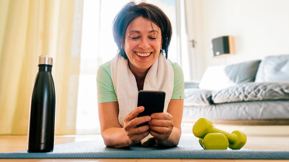 kobieta na macie patrzy na komórkę