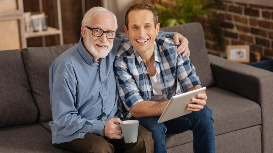 Dwaj mężczyźni siedzą na kanapie. Jeden jest starszy, a drugi młody.