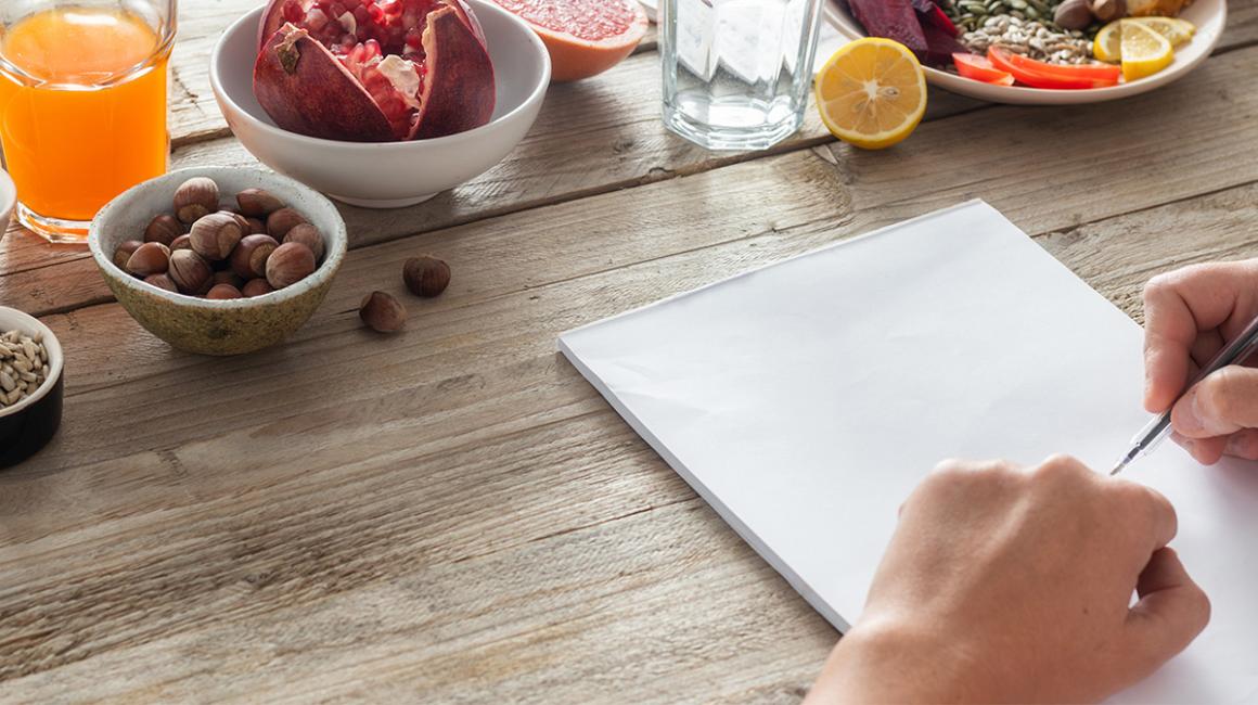 ręce z kartką i długopisem na stole z produktami żywieniowymi