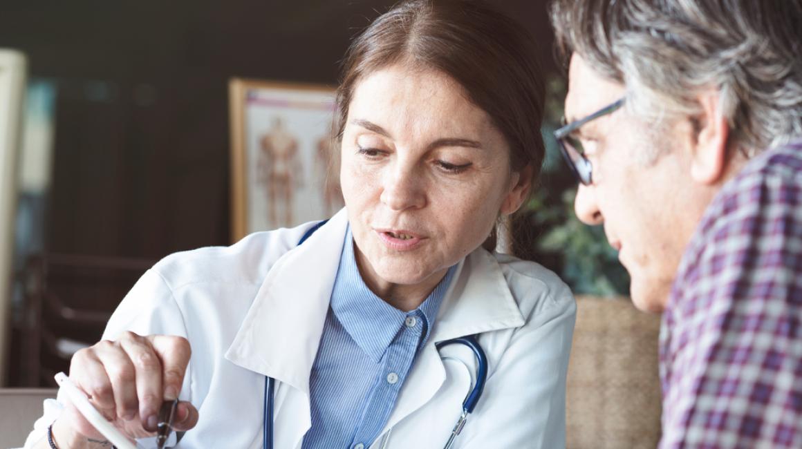 Lekarka omawia wyniki badań z pacjentem, który jest mężczyzna w 50 roku życia.