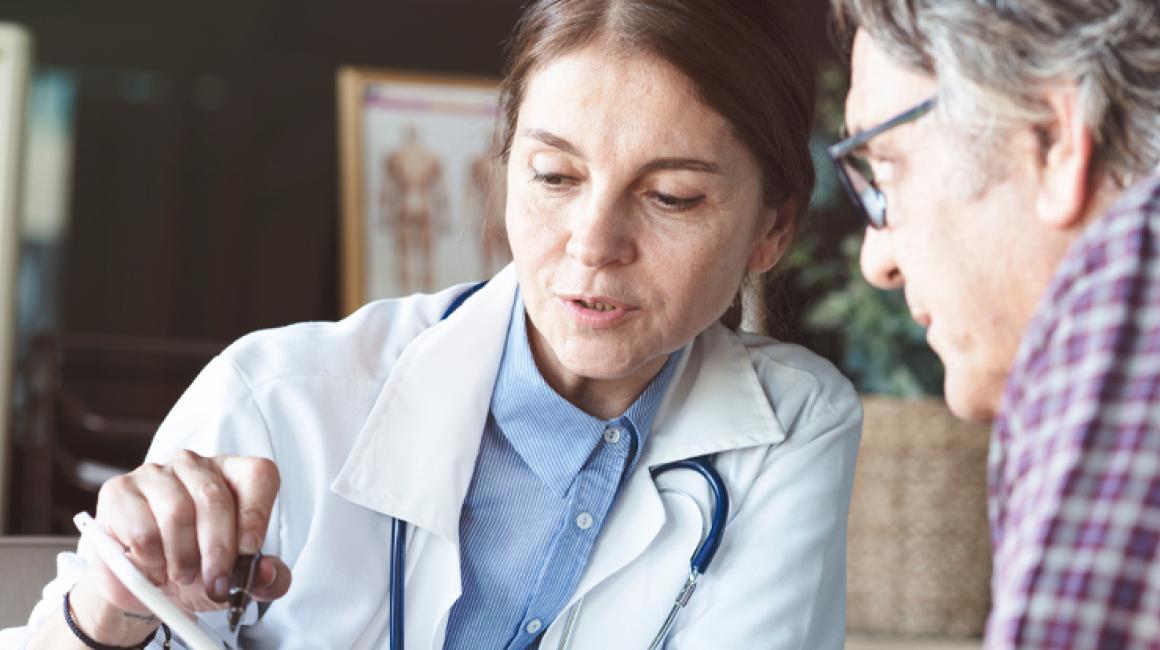 Lekarka omawia wyniki badań z pacjentem, który jest mężczyzna w 50 roku życia.