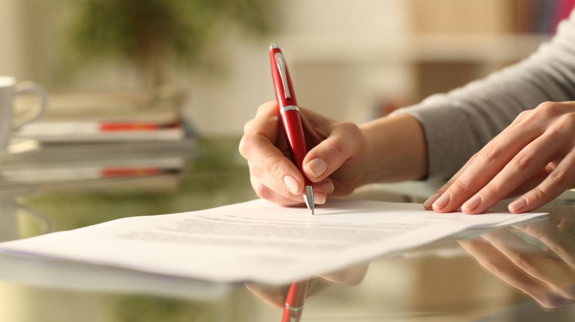 Damskie dłonie wypełniają formularz. 