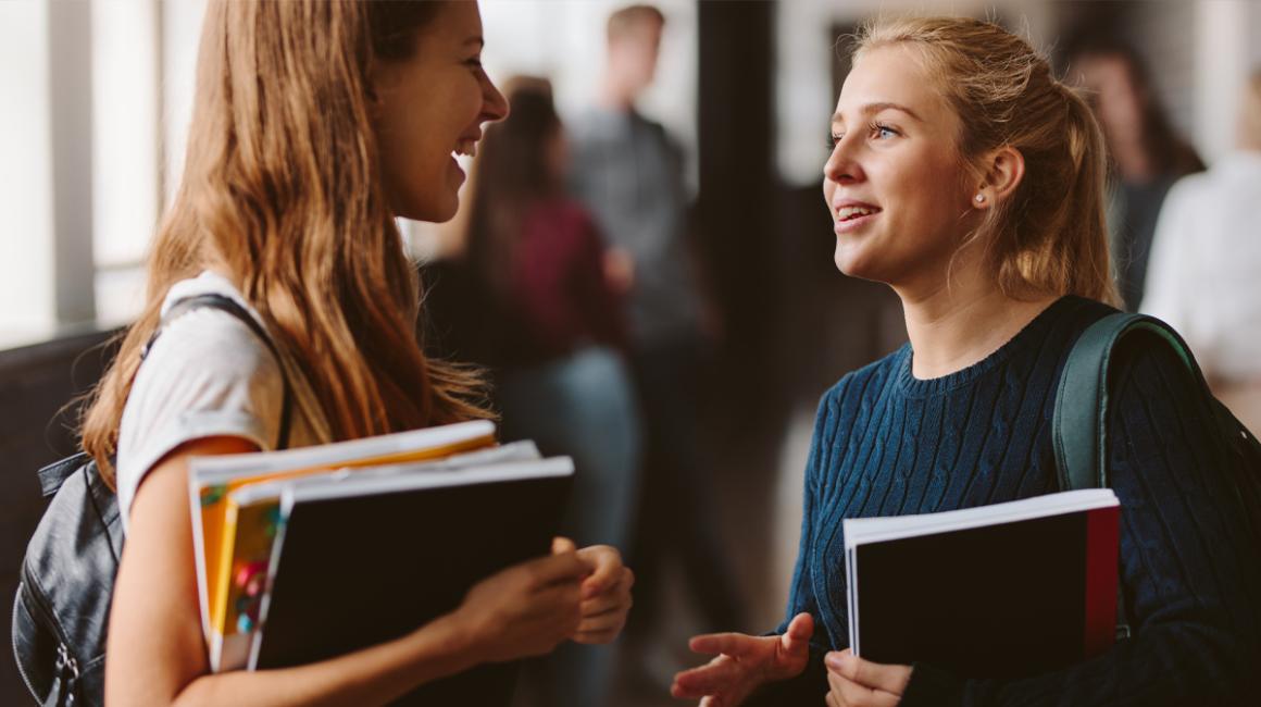 Dwie studentki rozmawiają na korytarzu.