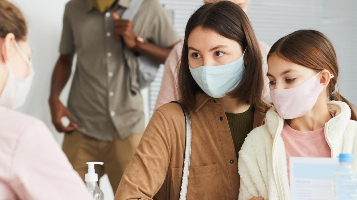 Przychodznia, matka z córką na kolanach zapisuje się na wizytę do specjalisty.