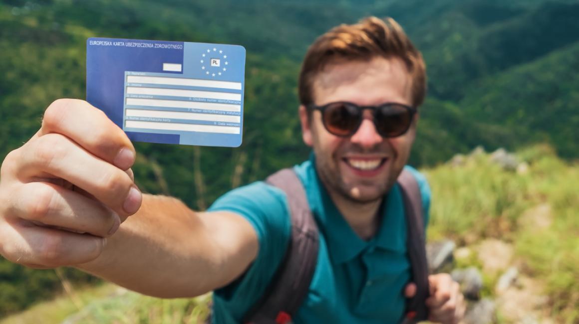 Turysta pokazujący kartę EKUZ. W tle góry
