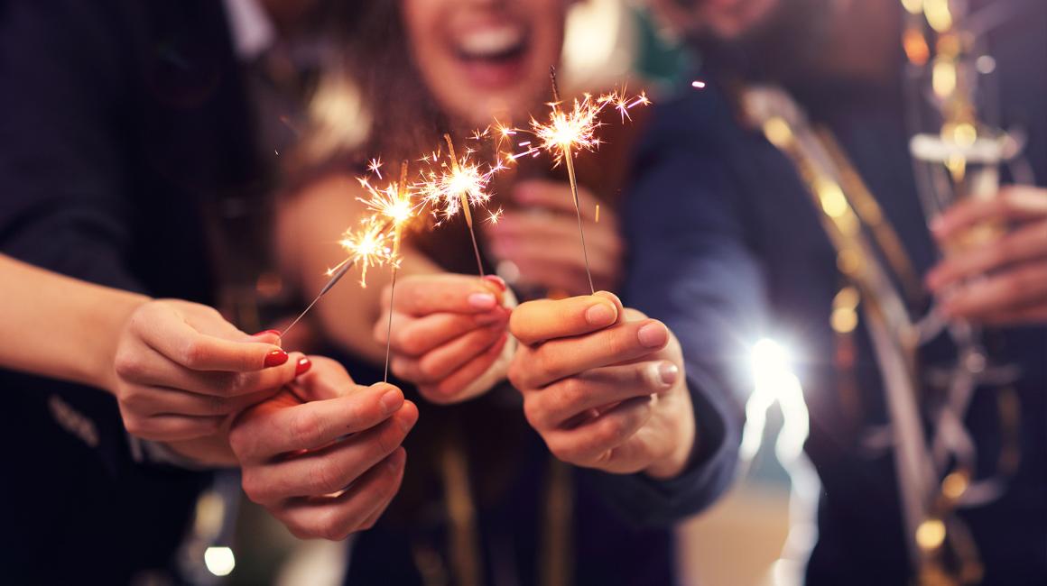 Palące się sztuczne ognie trzymane w dłoniach.