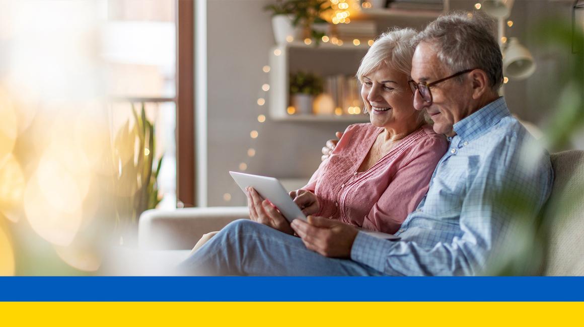 Starsza para na kanapie patrzy na tablet ukr