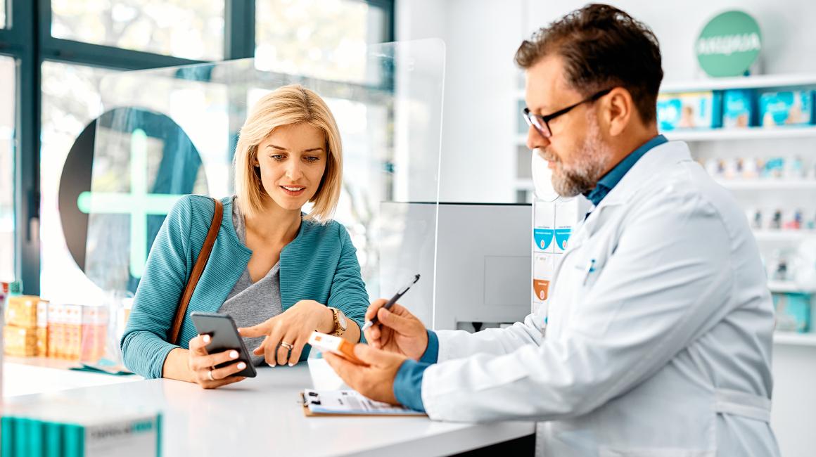 pacjentka z telefonem w aptece rozmawia z farmaceutą