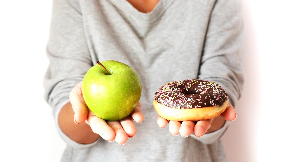 w jednej ręce jabłko, w drugiej ciastko