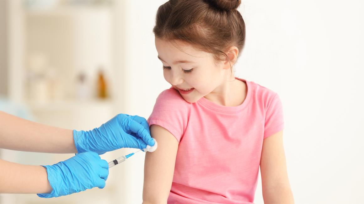 Widać ręce pielęgniarki i szczepioną kilkuletnią dziewczynke