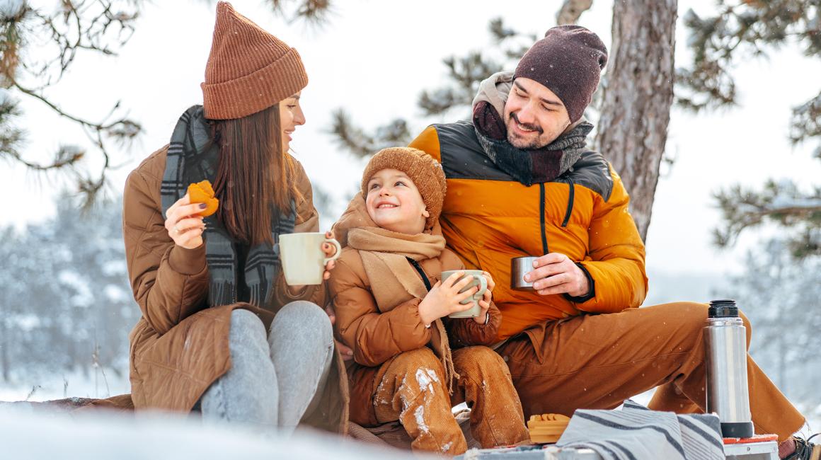 rodzinka w zimowym lesie pije herbatę z termosu