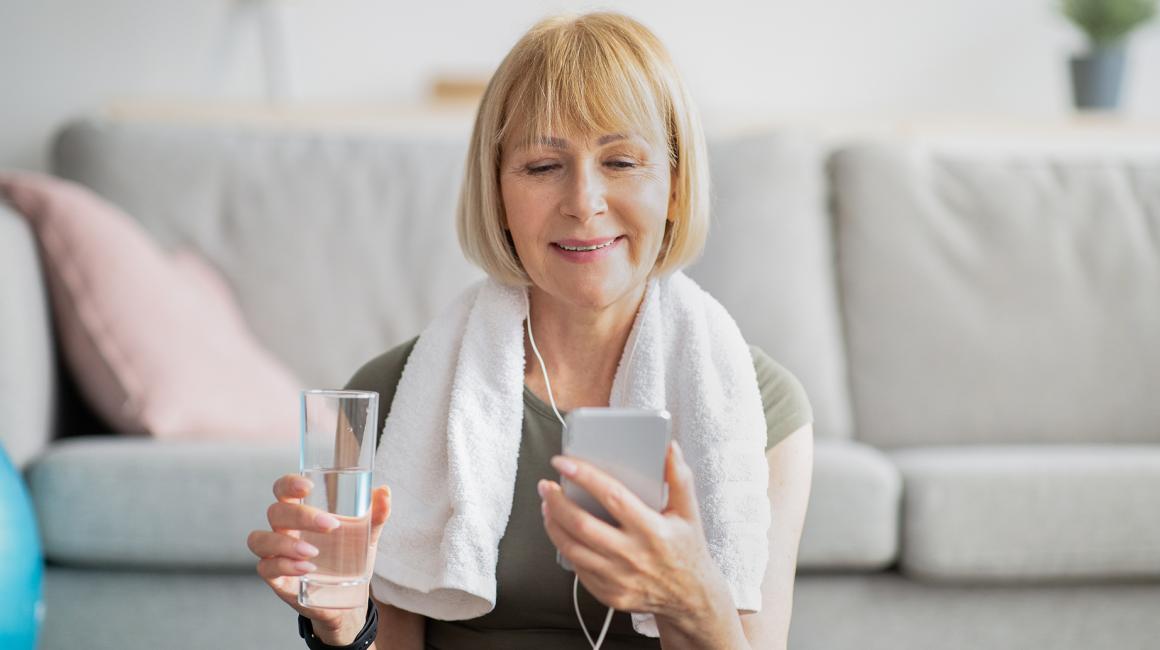 Kobieta po ćwiczeniach patrzy na telefon