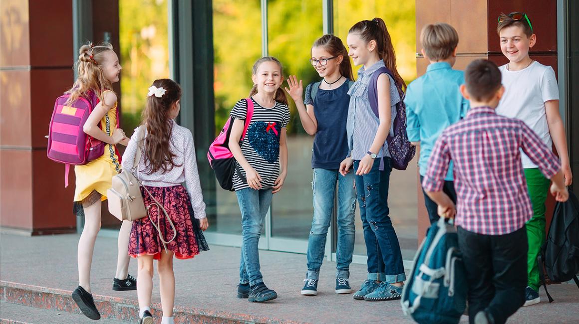 Grupa dzieci wita się przed szkołą
