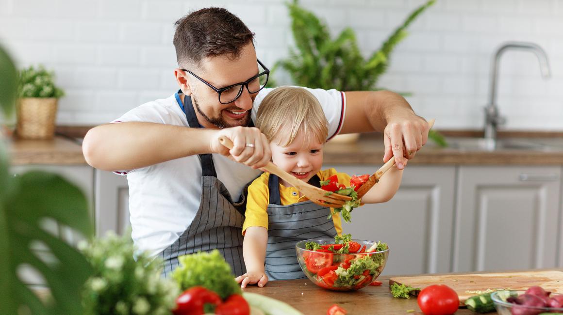 Tata z dzieckiem w kuchni robi sałatkę