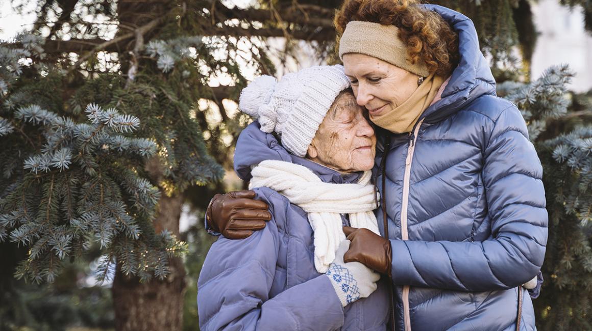 50latka przytula starszą panią, obie w kurtkach i czapkach