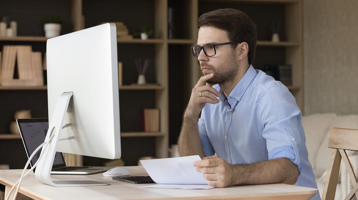 Mężczyzna z papierami przed komputerem