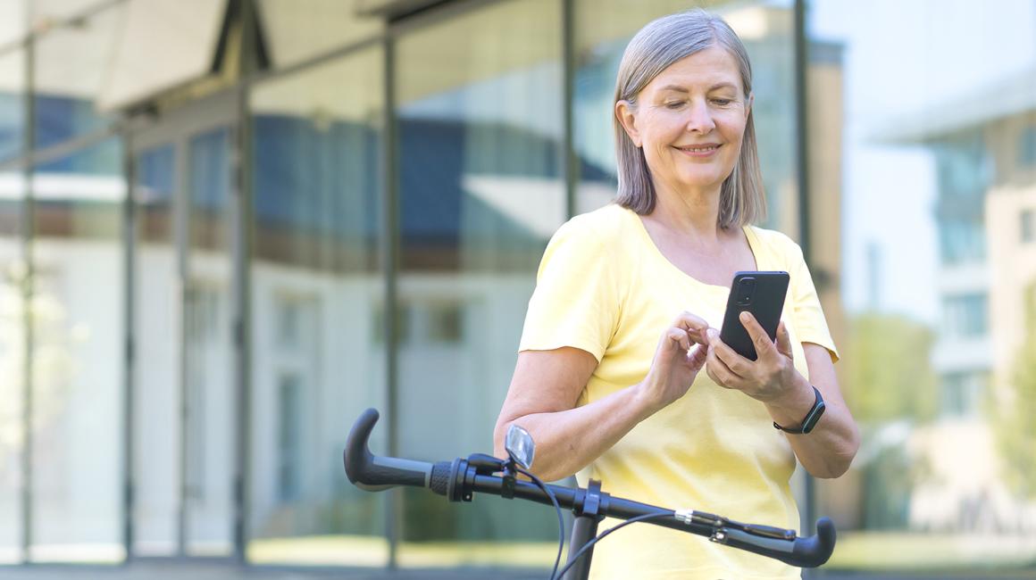 Kobieta przed biurowcem sprawdza coś w komorce