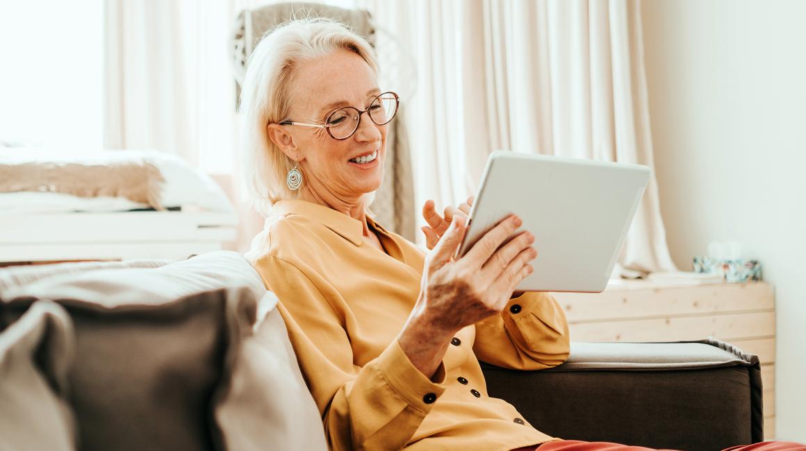 Starsza pani w żółtej bluzce z tabletem