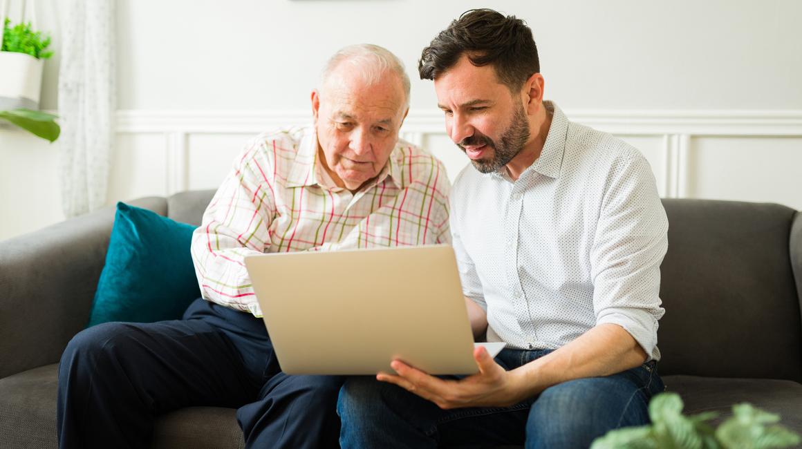 Starszy Pan i mlody facet z brodą na kanapie z laptopem