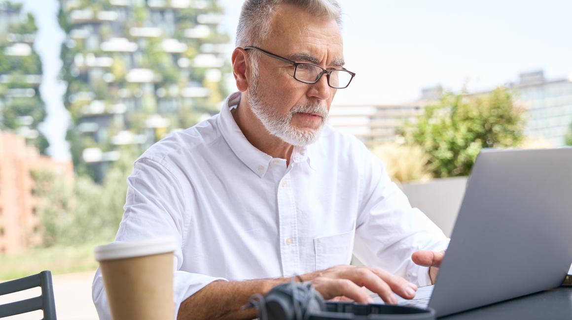 mężczyzna z brodą w białej koszuli przy komputerze