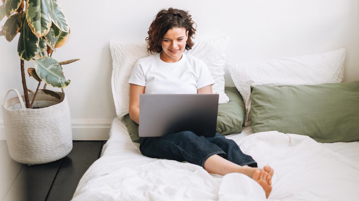 Kobieta siedzaca na łozku z laptopem