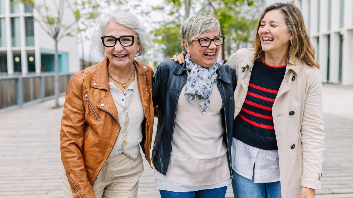 trzy panie w roznym wieku ida ulica rozesmiane i objete 