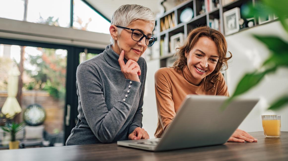 dwie panie nad laptopem, jedna ma siwe włosy