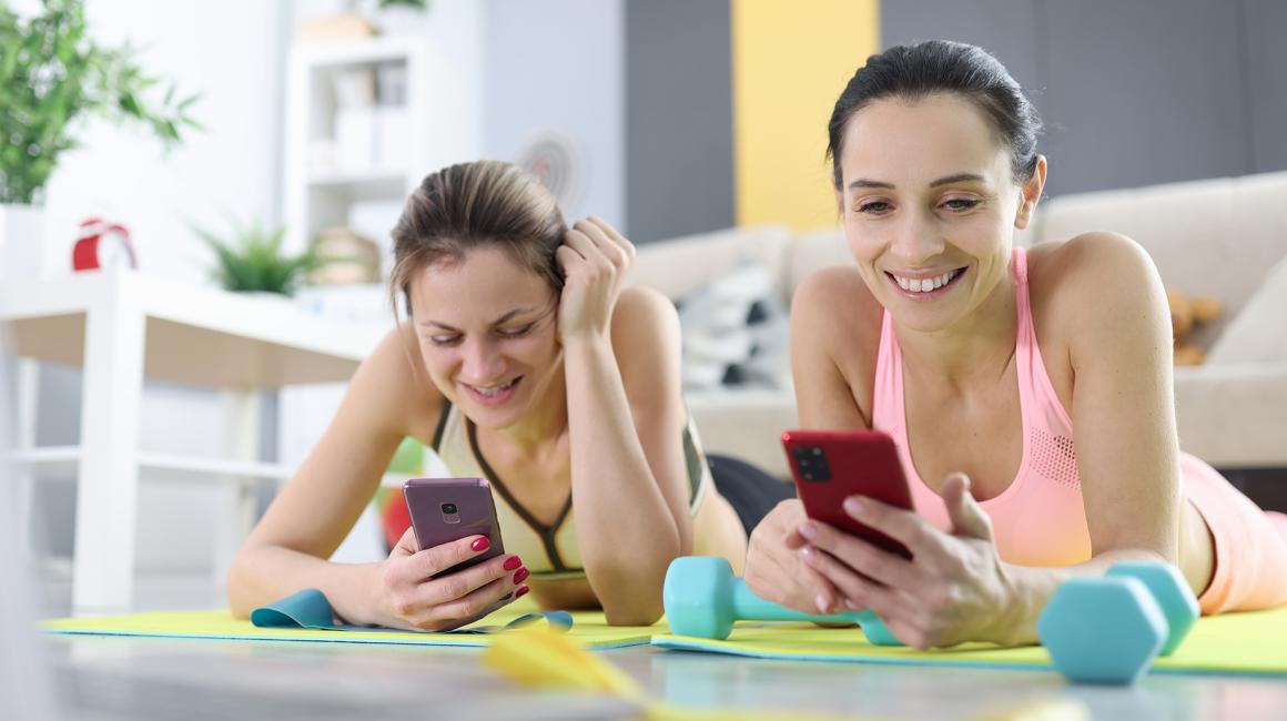 dwie młode dziewczyny ćwiczą w domu z telefonem