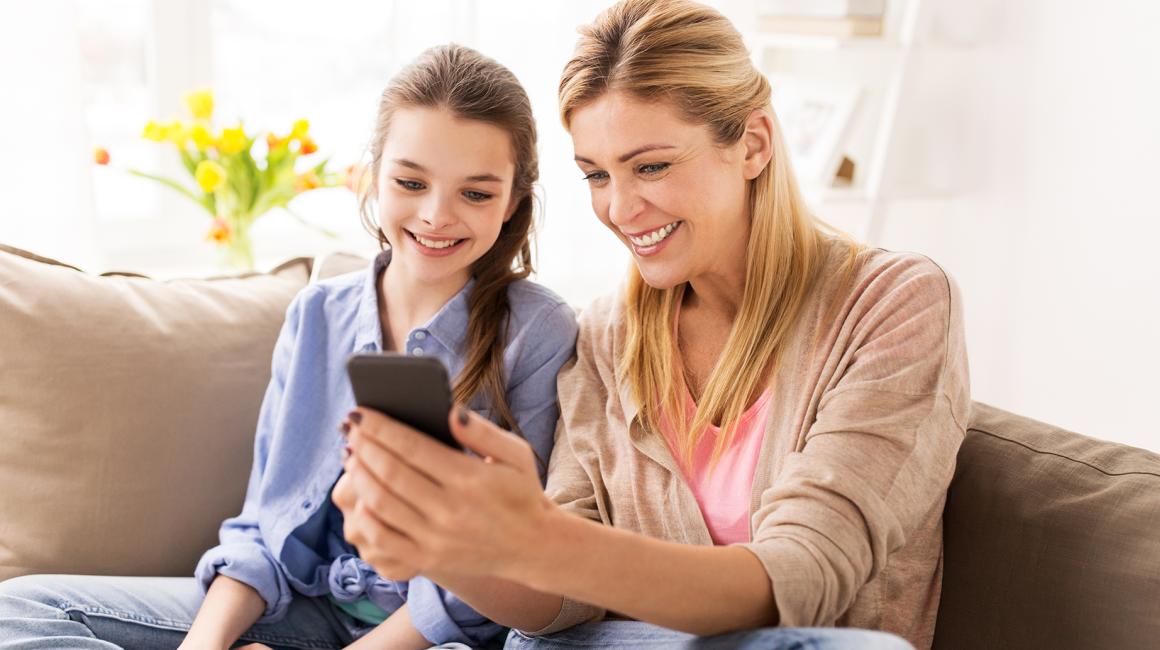 matka z komórką w ręku z córka na kanapie