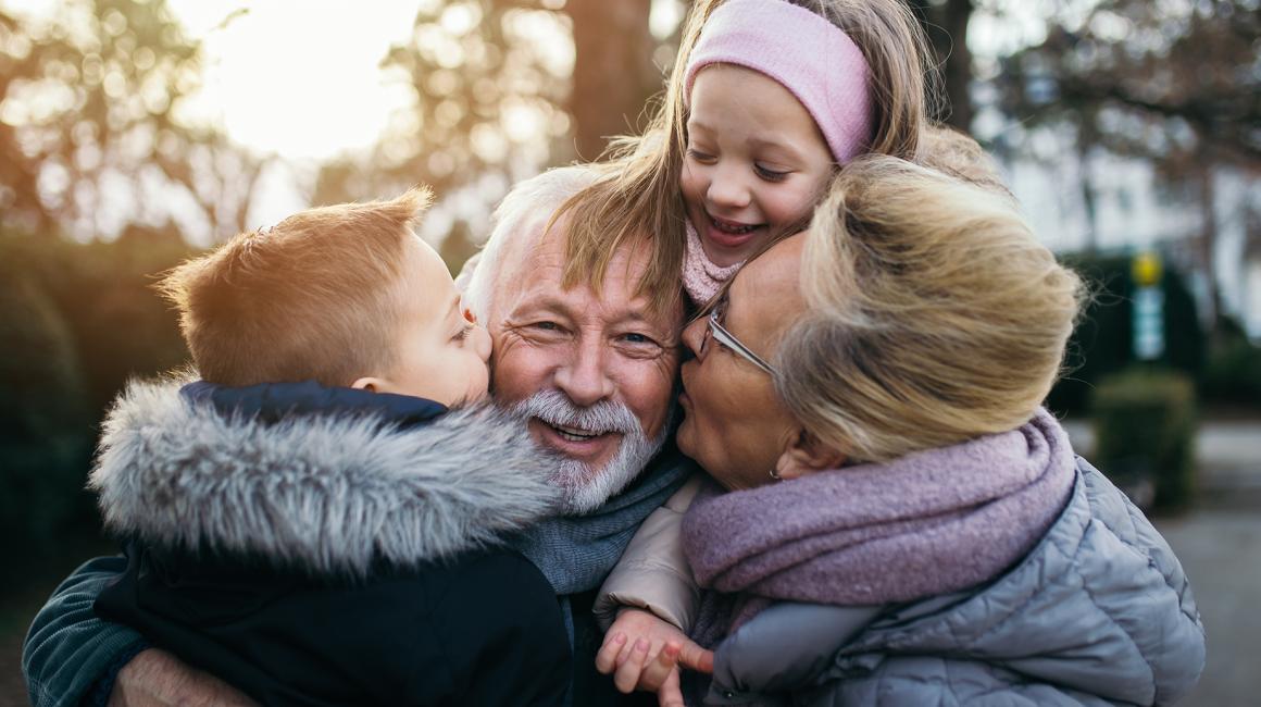 Dziadek, babcia, sciskające go wnuki