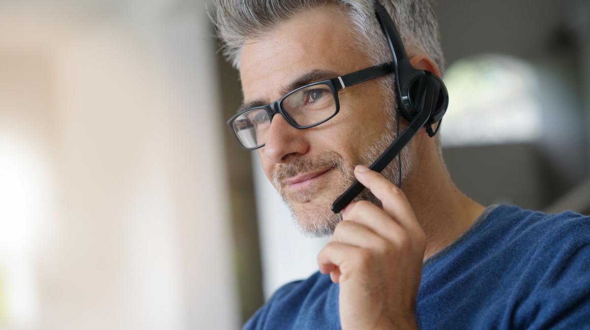 mężczyzna w słuchawkach na głowę, w okularach, siwe skroniie