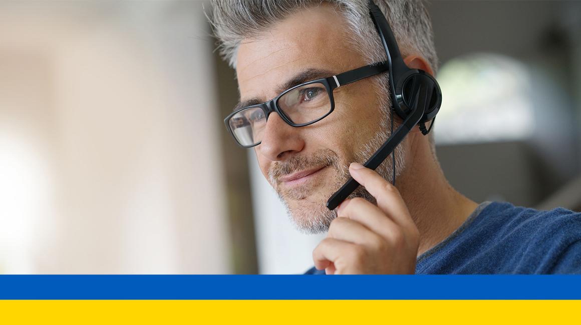 mężczyzna w słuchawkach na głowę, w okularach, siwe skroniie ukr flaga