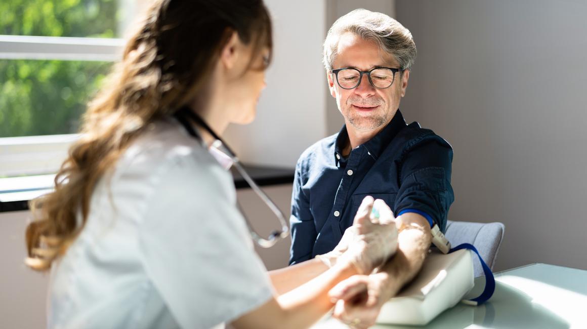 Lekarka pobiera krew starszemu mężczyźnie w okularach.