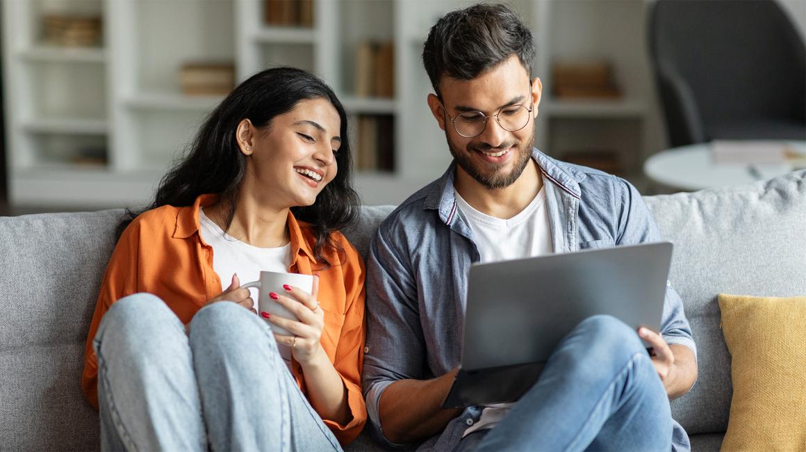 Para na kanapie, młodzi, zadowoleni, chlopak z laptopem