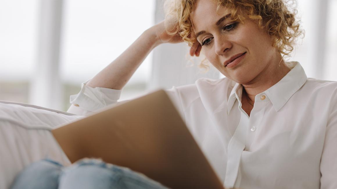 kobieta z laptopem na kolanach, w białej bluzce