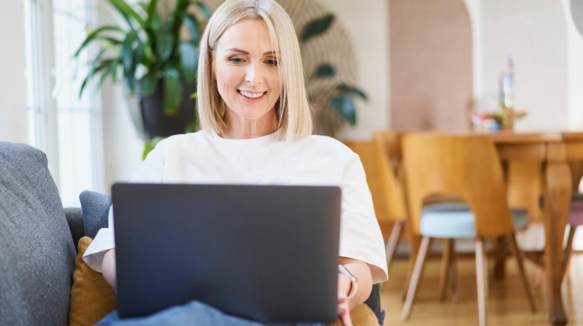 Kobieta w białym t-shircie z laptopem na kanapie