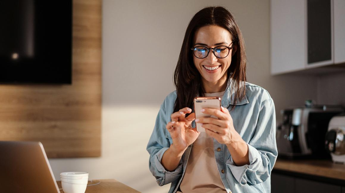 młoda szatynka z telefonem w swojej kuchni