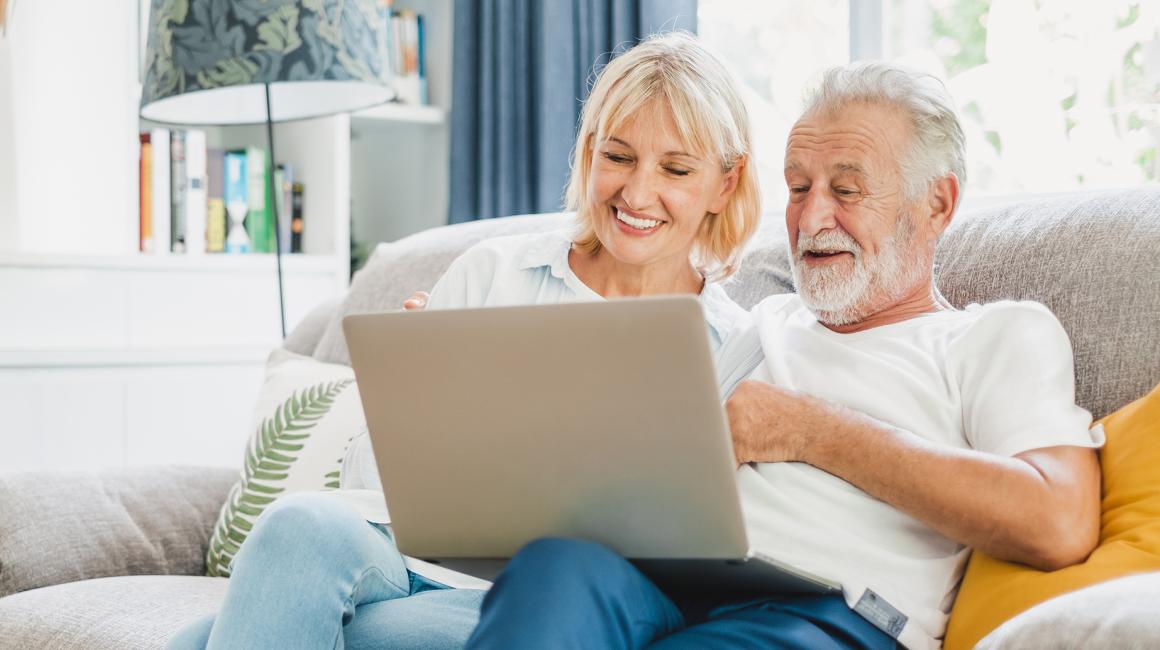 para w średnim wieku na kanapie z komputerem