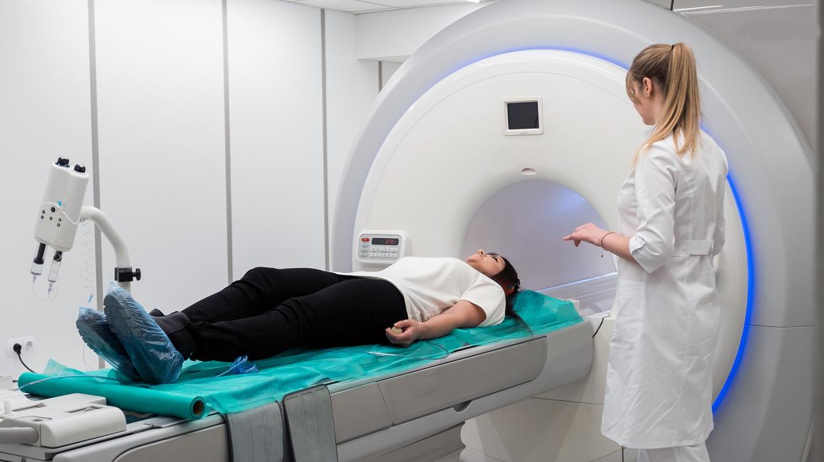 osoba wjeżdża do tuby obok stoi pielegniarka