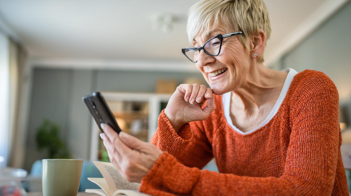 Starsza pani w czerwonej bluzce z telefonem w ręku