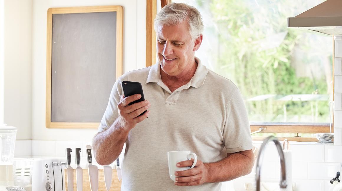 50latek w kuchni patrzy na telefon