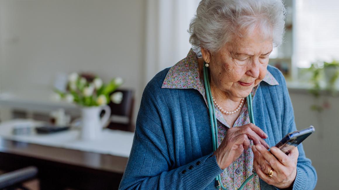Starsza pani wybiera coś na komorce