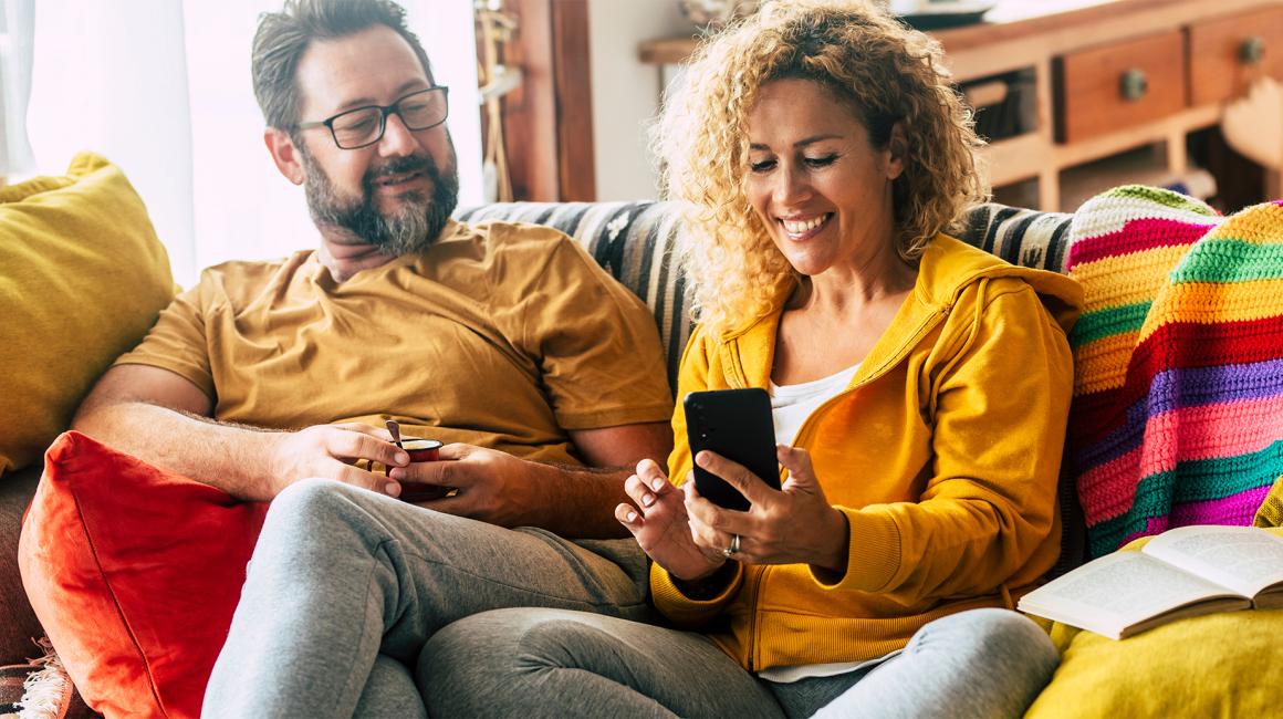 para na kanapie, uśmiechnięci, ona z telefonem