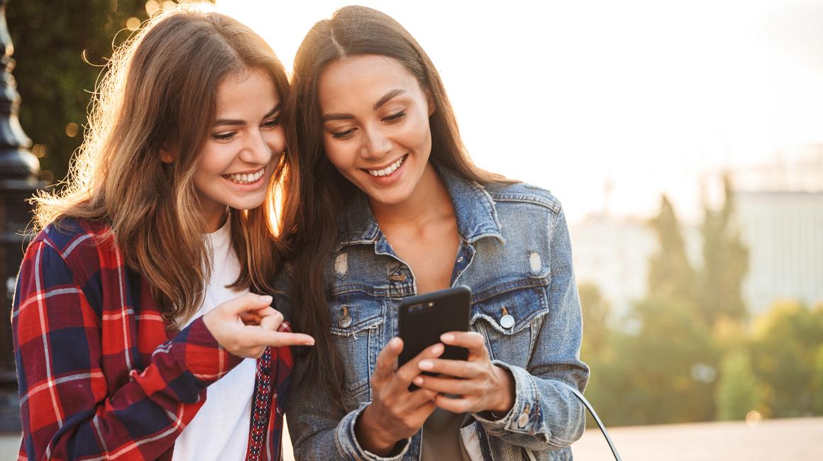 kobieta we flanelowej koszuli pokazuje drgiej coś na jej komórce